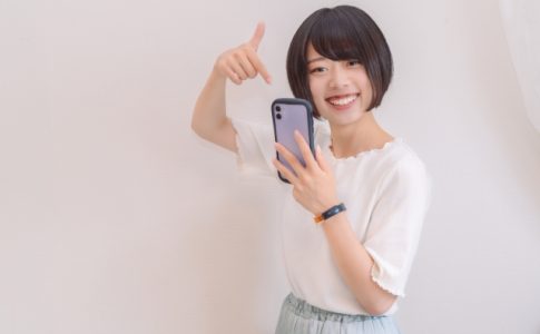 スマホを指さして笑顔の女性