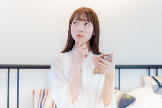 スマホをもって斜め上を見る女性